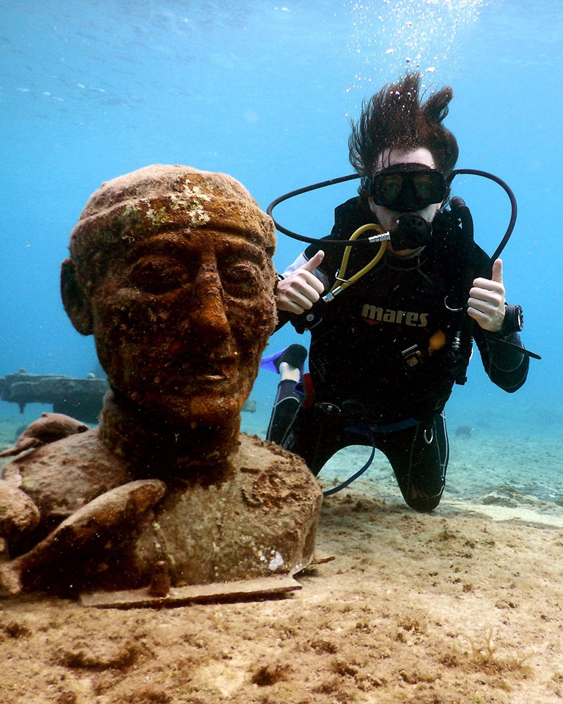 Wedding videographer scuba diving near underwater statue