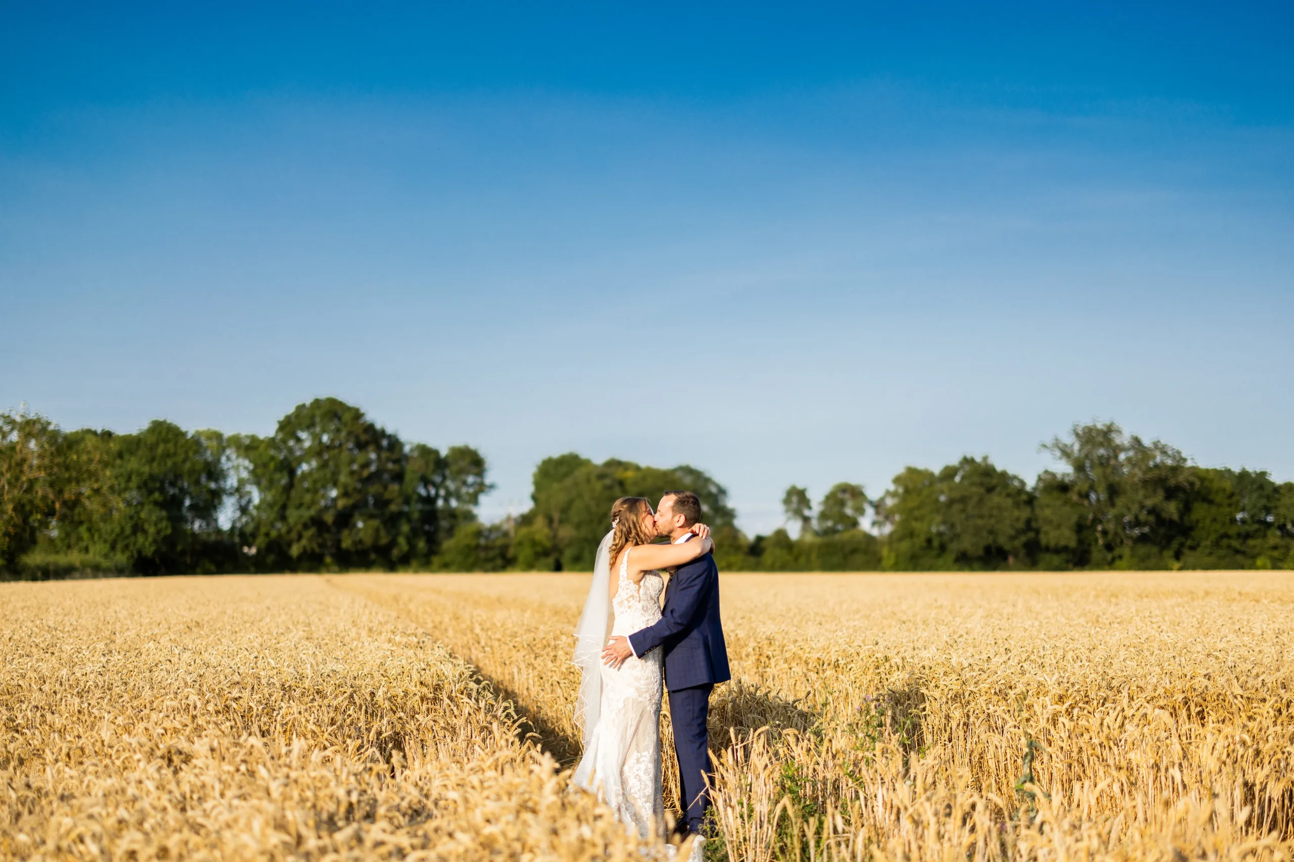 Romantic wedding photographer capture of couple embracing in wheat field
