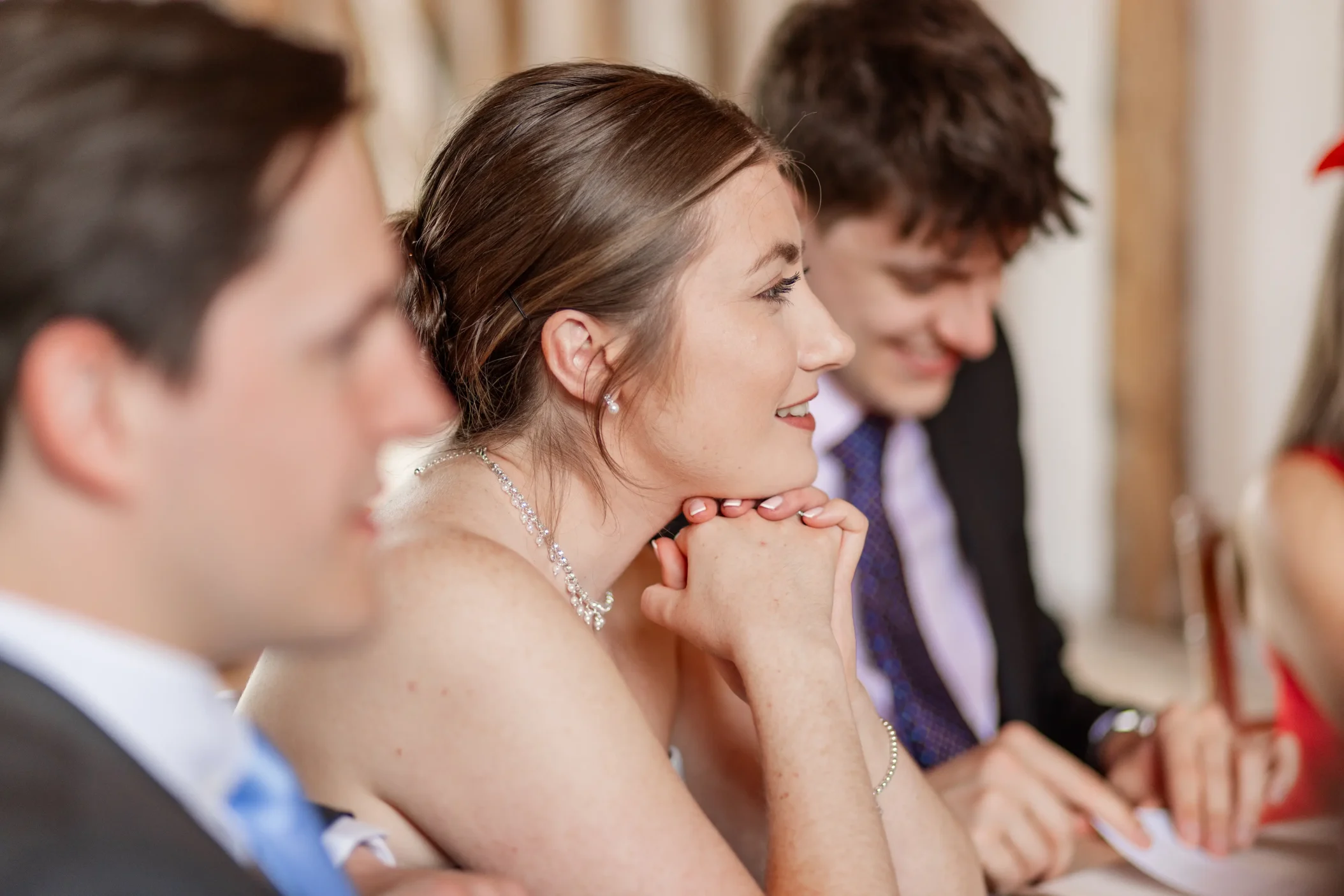 A bridesmaid smiling during wedding speeches in a candid wedding photography moment.