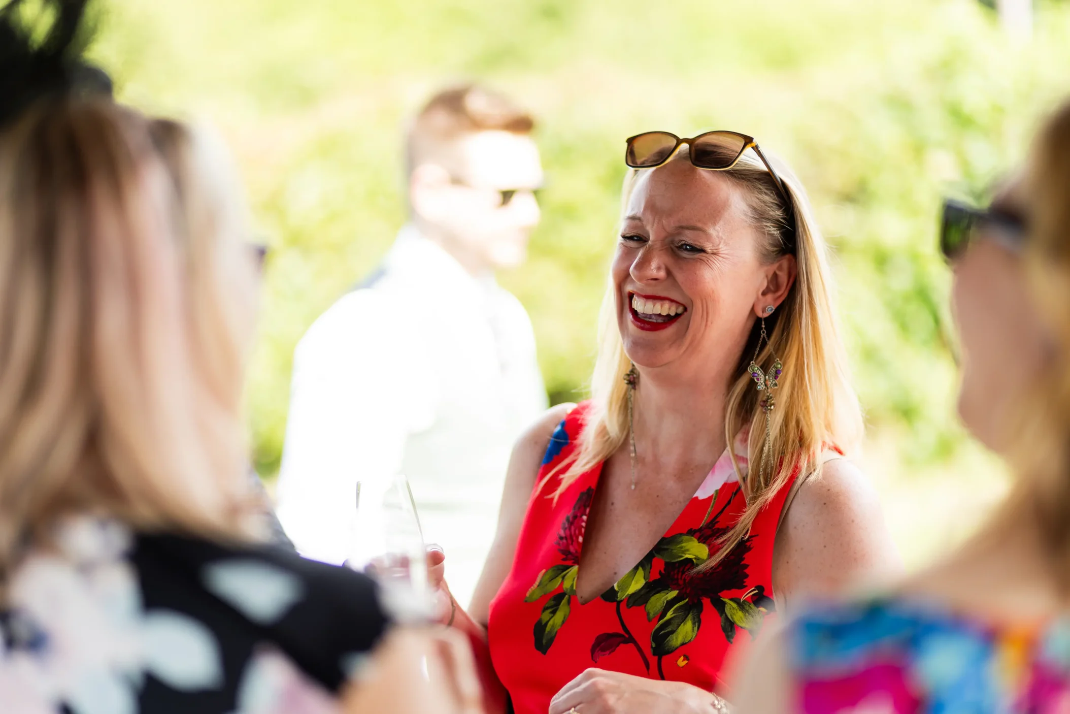A woman in a floral dress laughing in a candid moment captured in wedding photography.