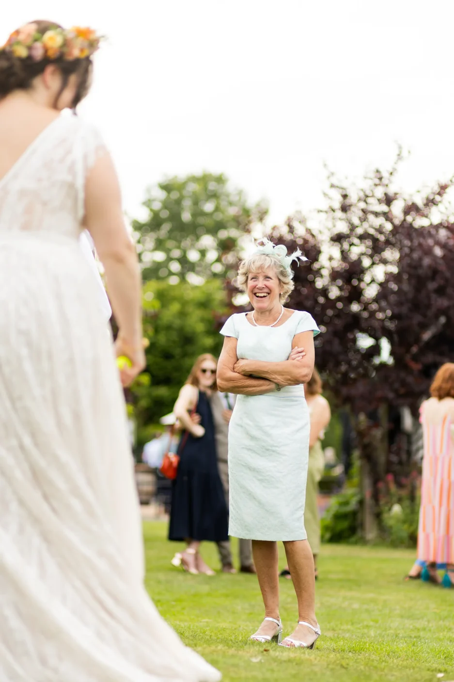 An elderly wedding guest smiling while holding a drink at the wedding reception beautifully documented in wedding photography.